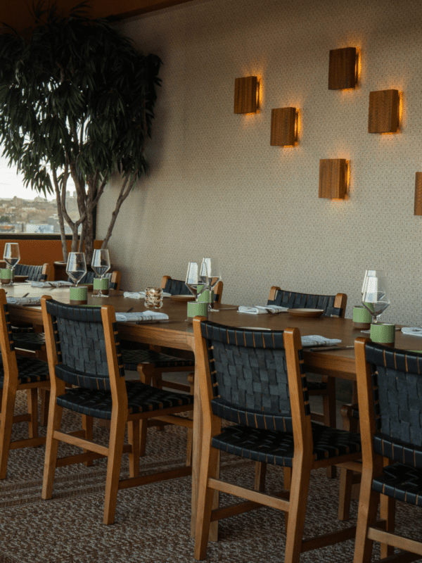 A dining area with a long wooden table, chairs, and wall lights.