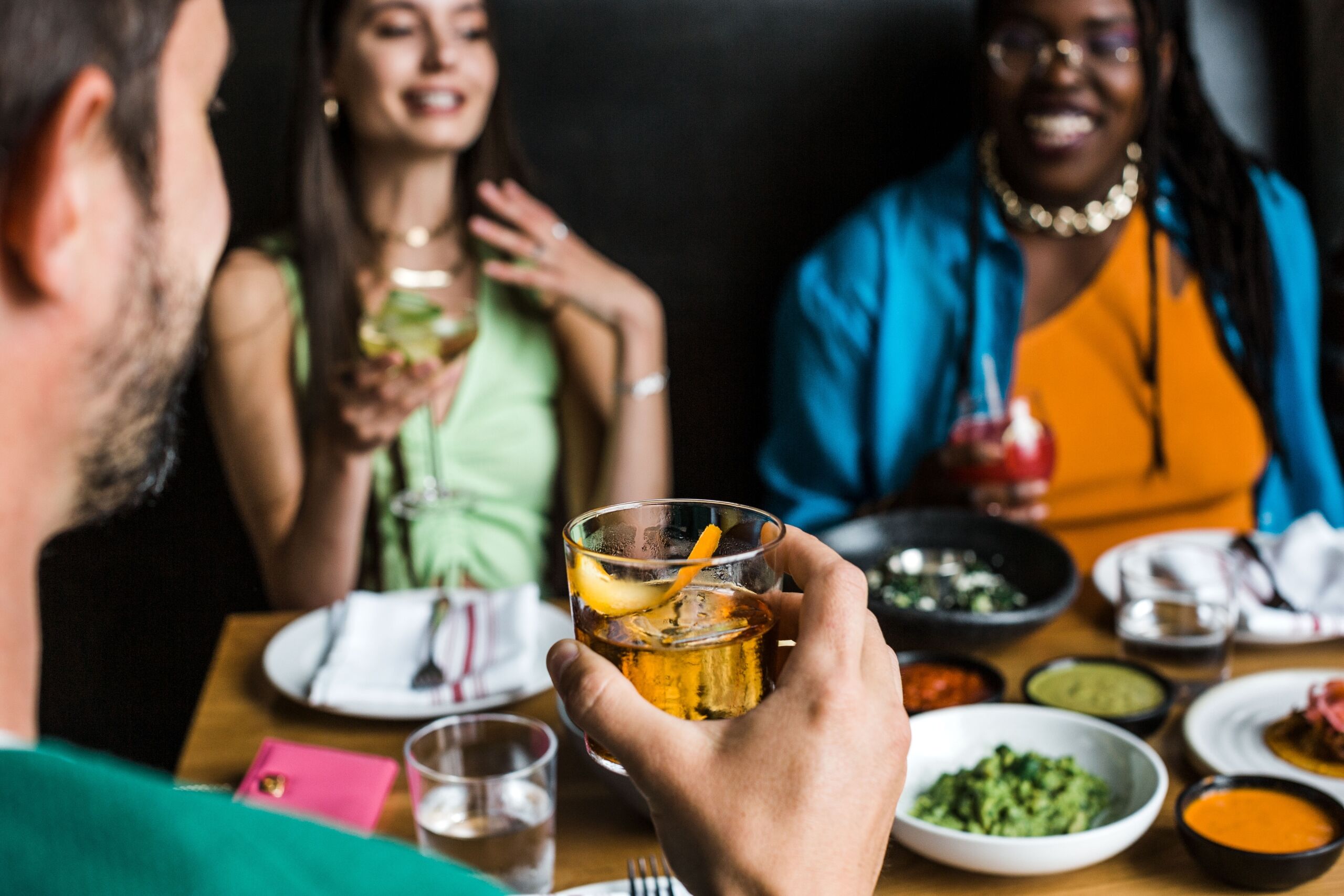 A group of people sitting at a table with food and drinks