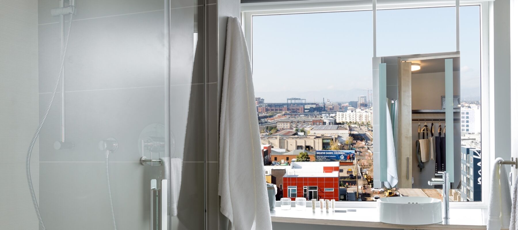A bathroom with a shower, sink, and city view