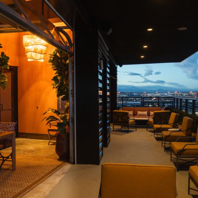 A balcony with outdoor seating and a city view at dusk.